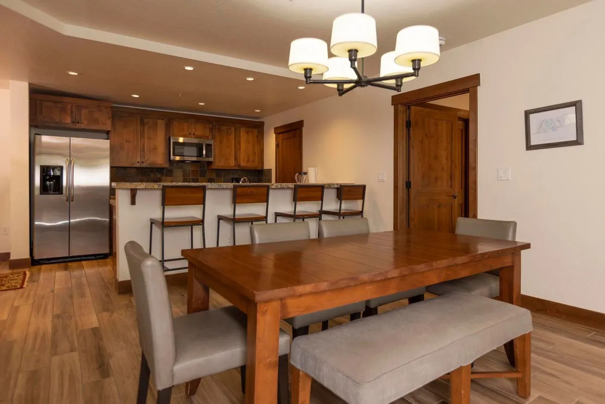 The photo showcases a spacious dining area complete with a large dining table, bar stools, and soft lighting. The inviting setup is perfect for shared meals, celebrations, and board games with family or friends, reinforcing the communal aspect of the space.