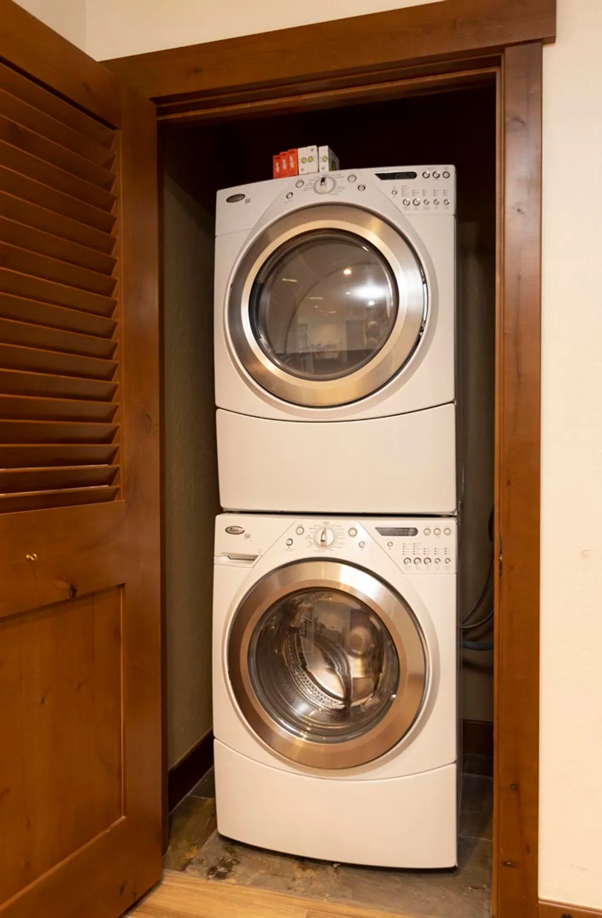 The image showcases a practical laundry area with a stacked washer and dryer, enhanced by warm wooden door and paneling elements. The ambiance is tidy and functional, reinforcing the idea of convenience and comfort for guests during their getaway.